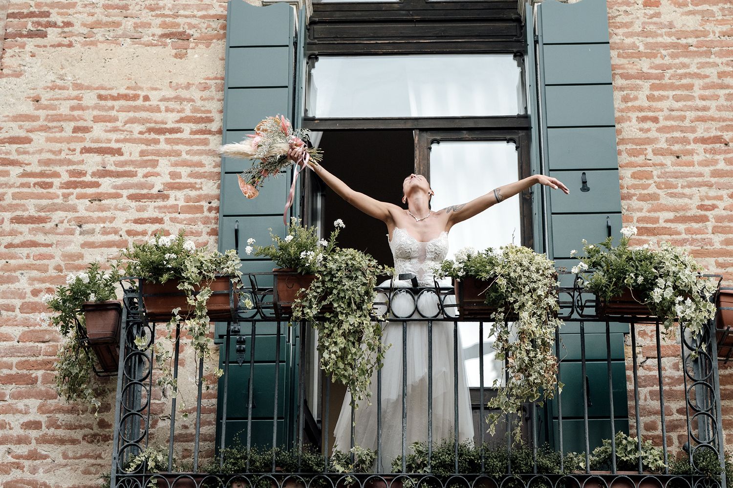 Wedding venue exterior features rustic brick walls and green shutters with floral decorations.