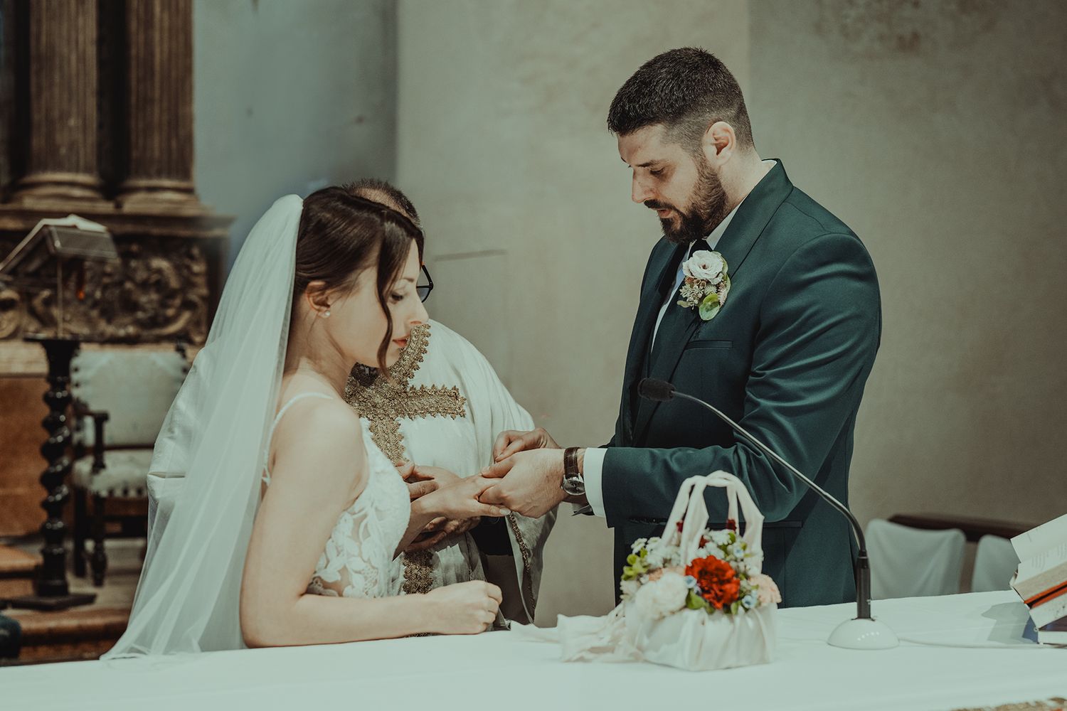 A couple exchanges rings during their wedding ceremony at an elegant church altar.