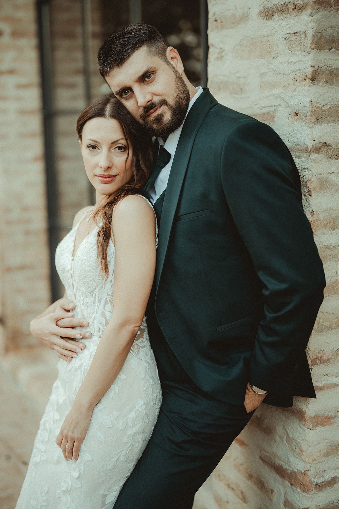 Intimate portrait session against a rustic brick wall showing tender moments between a couple.