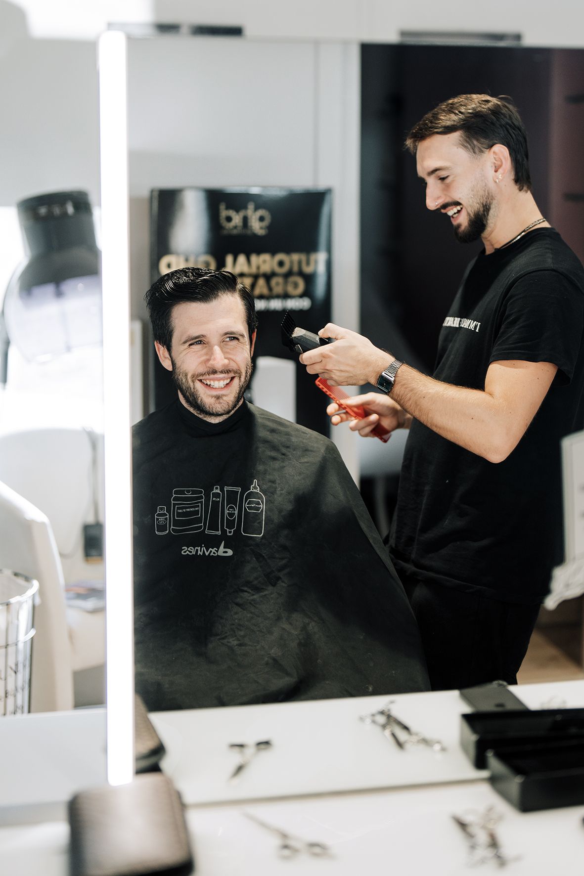 Barber styling client's hair in modern salon with bright interior.
