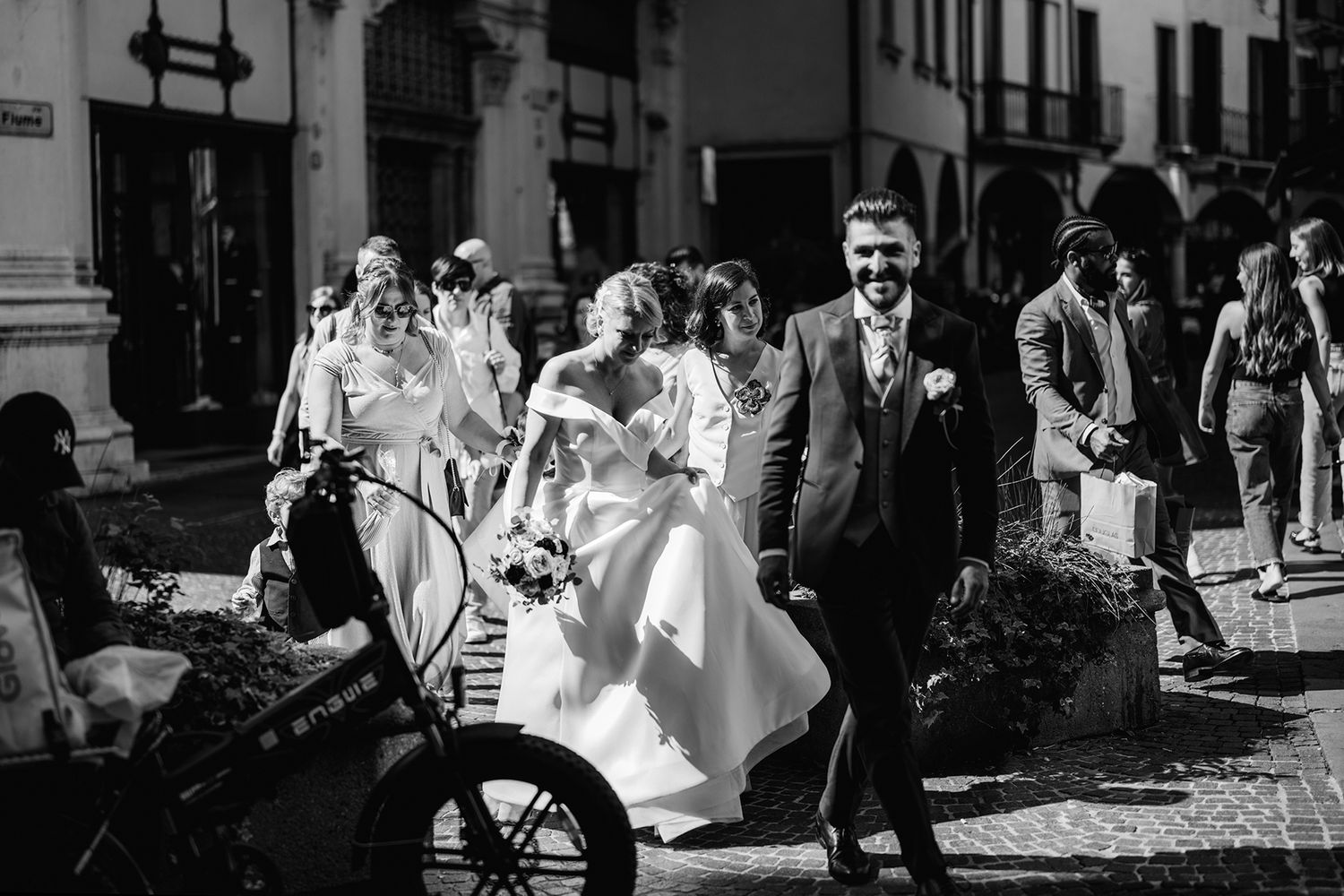 Black and white street photography of a wedding celebration in an urban setting.