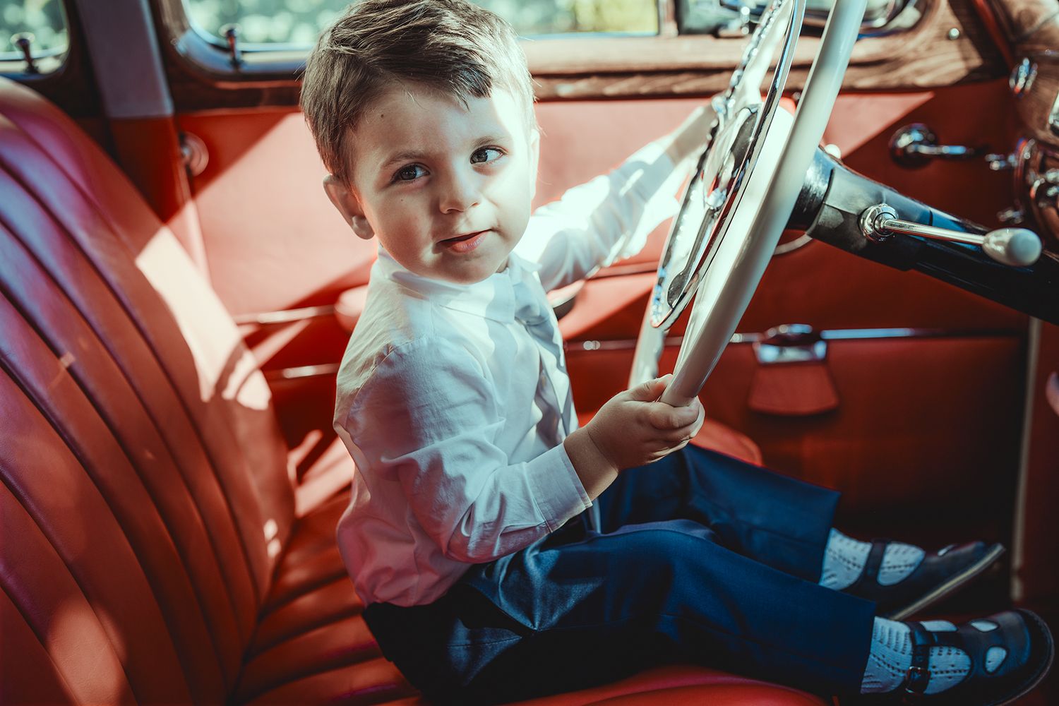 Red leather interior of a vintage automobile with dashboard details.