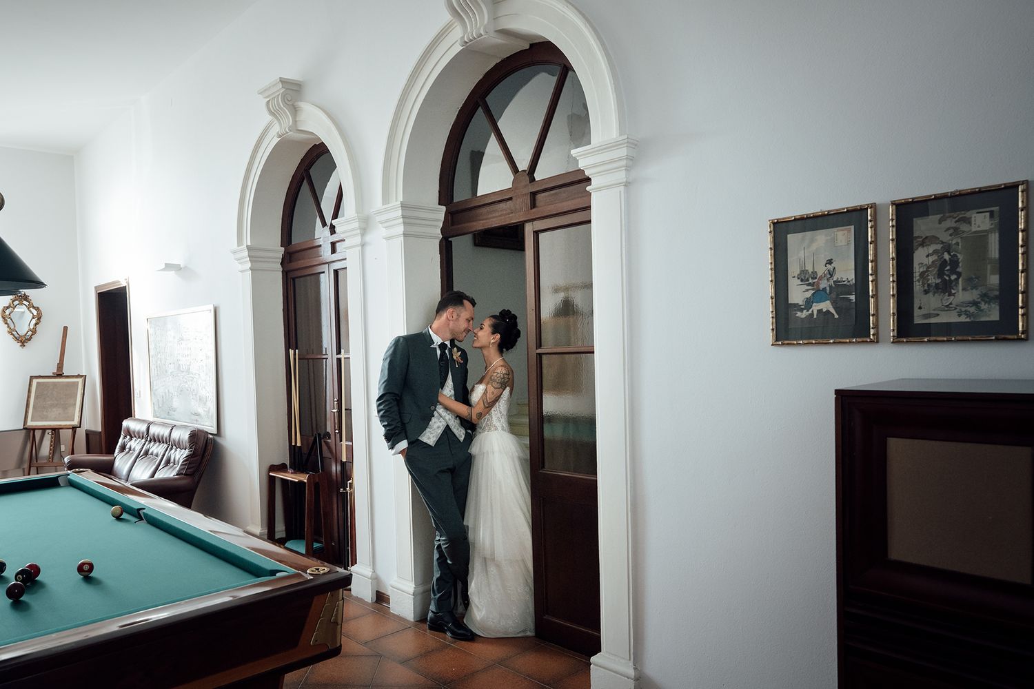 Creative wide-angle shots of newlyweds interacting in a bright indoor space with pool table.