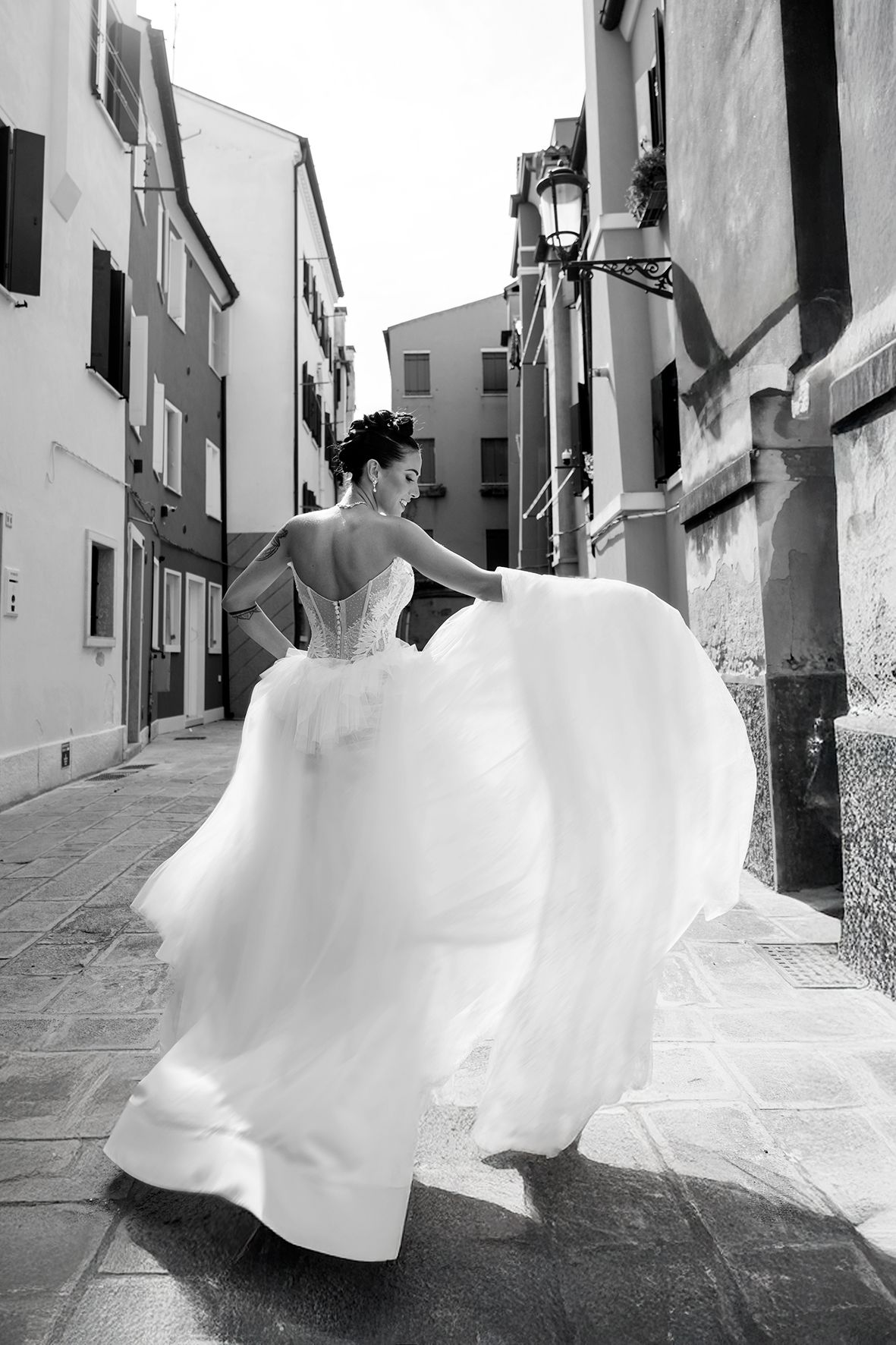 Dynamic bridal photos in a white dress against narrow European village streets.