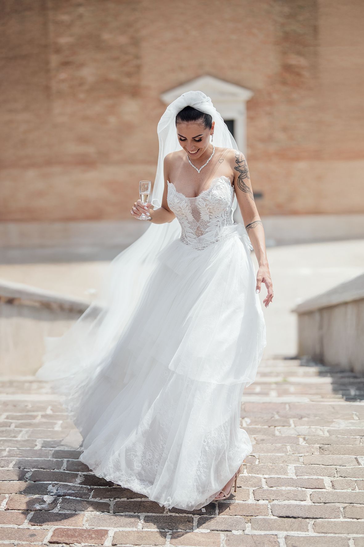 Bride in flowing white dress twirls on historic cobblestone streets.