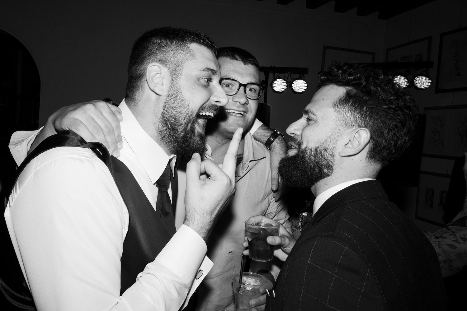 Candid black and white shots of wedding guests sharing laughter and drinks.