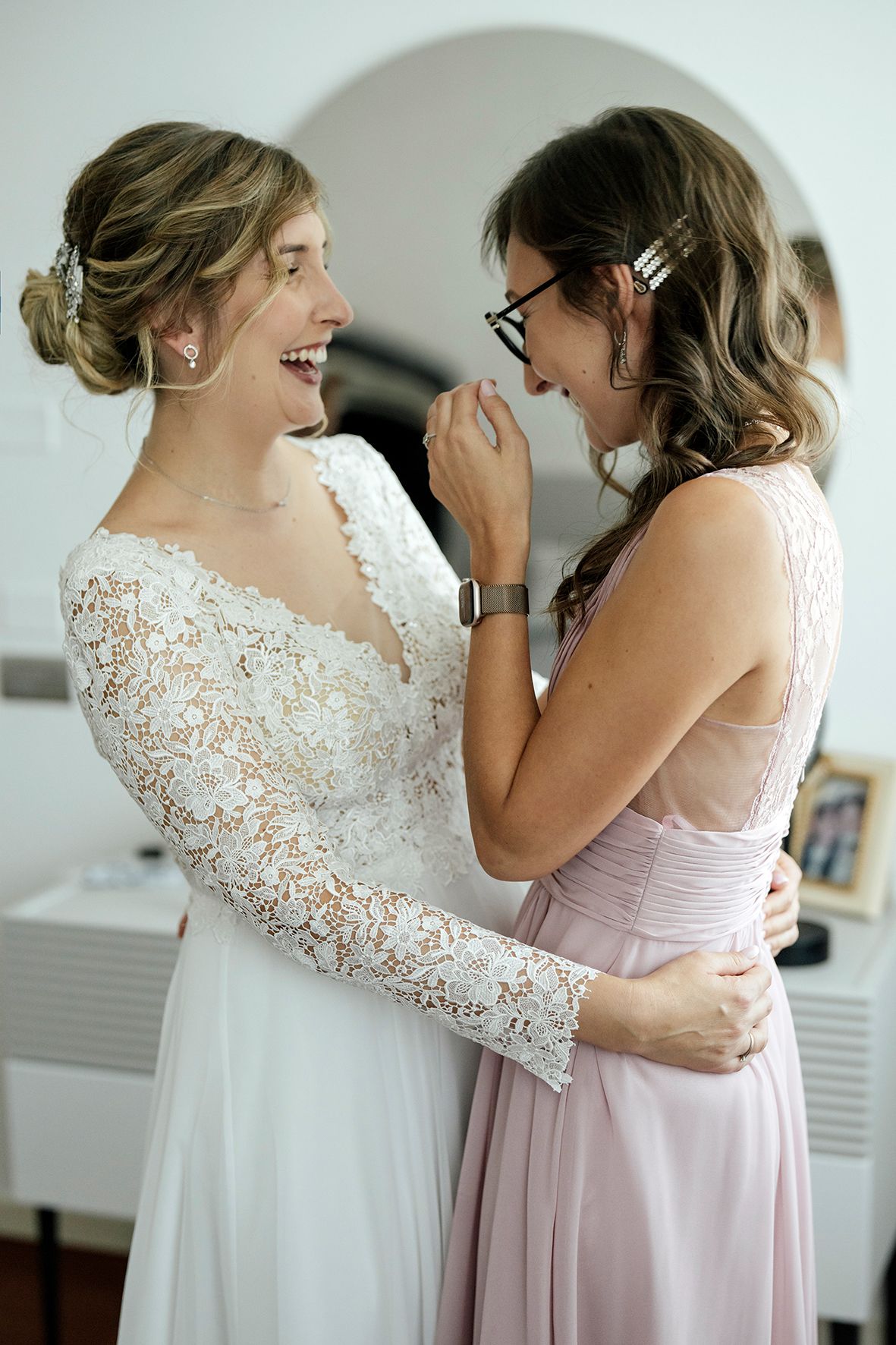 Emotional moment between two women in wedding attire sharing a heartfelt embrace.