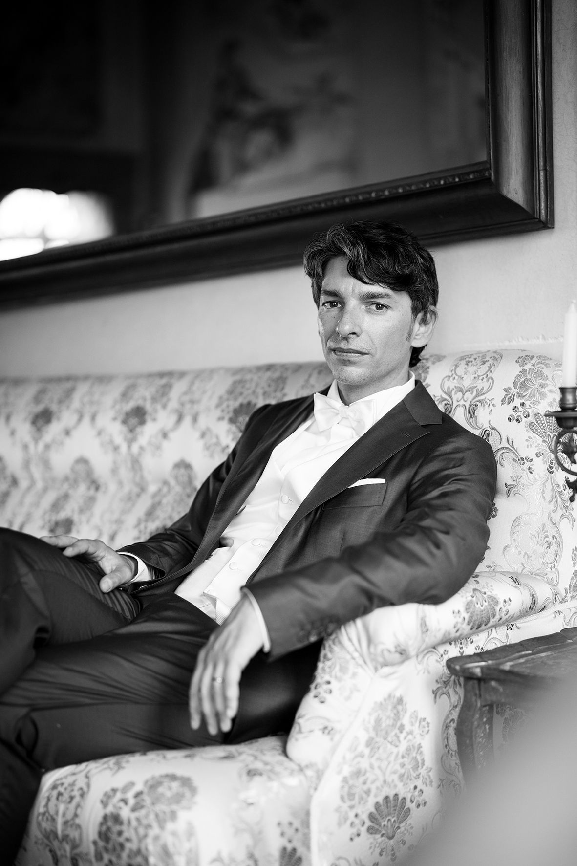 Black and white portrait on a floral patterned couch showing elegant formal attire.