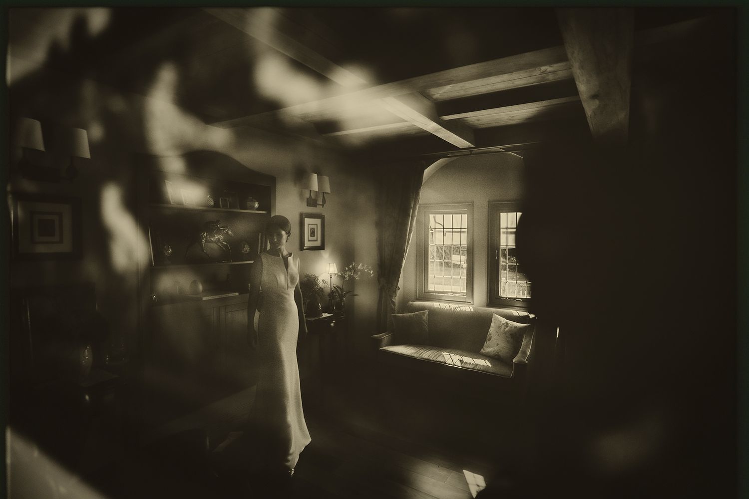 Moody black and white vintage photograph showing sunlight streaming through a window into a dark interior room.