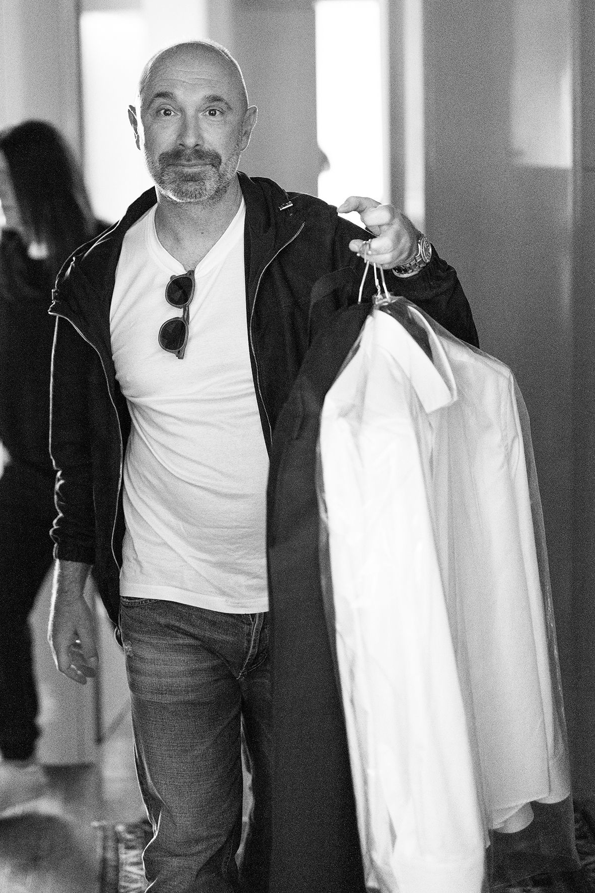 Black and white photos showing a person in a white t-shirt and dark jacket walking through a hallway.