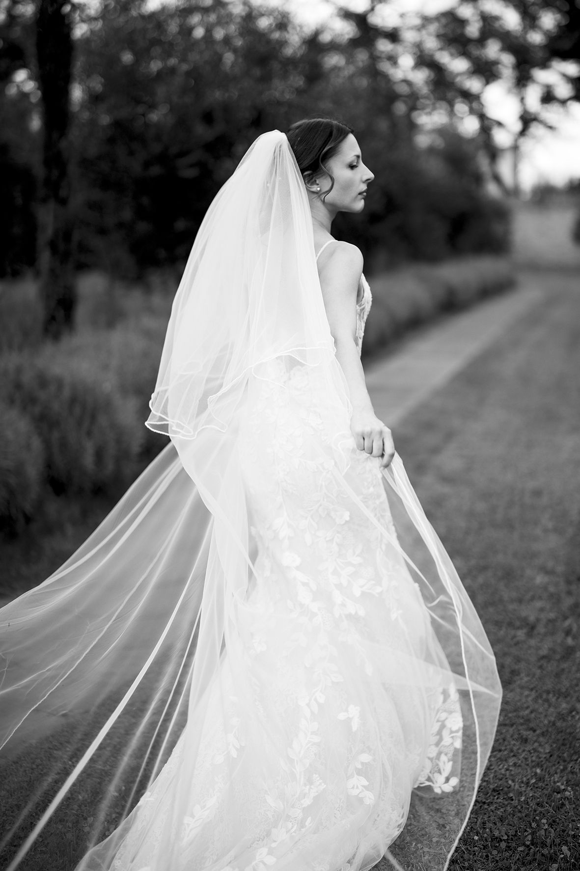 Dramatic black and white photo of flowing wedding veil in an outdoor garden setting.