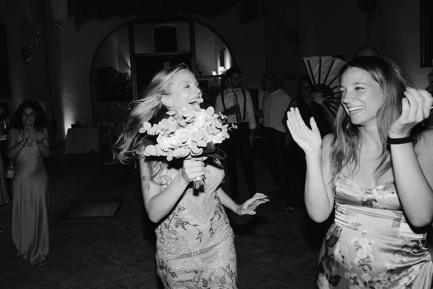 Wedding party guests dancing together in a dimly lit reception venue.