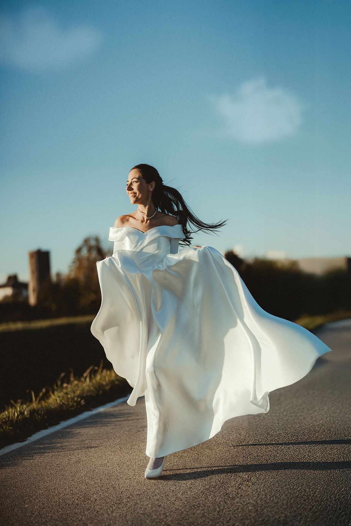 Elegant white wedding dress movement captured against blue sky backdrop.