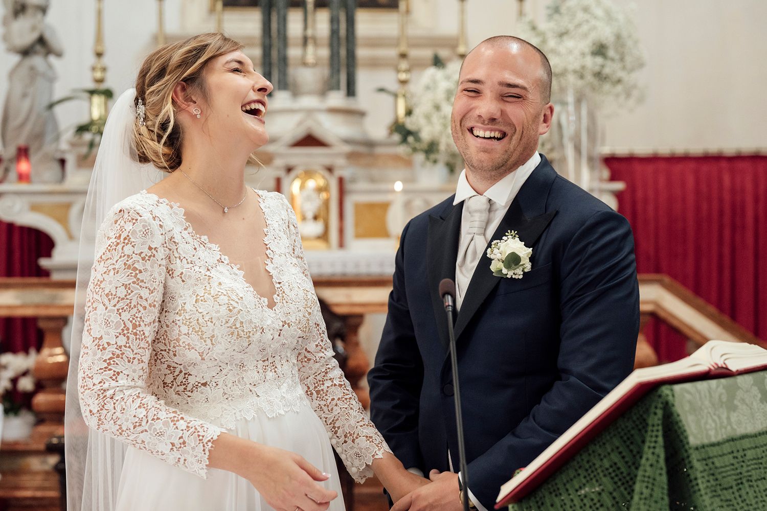 Couple laughs together during their wedding ceremony in an elegant church setting.
