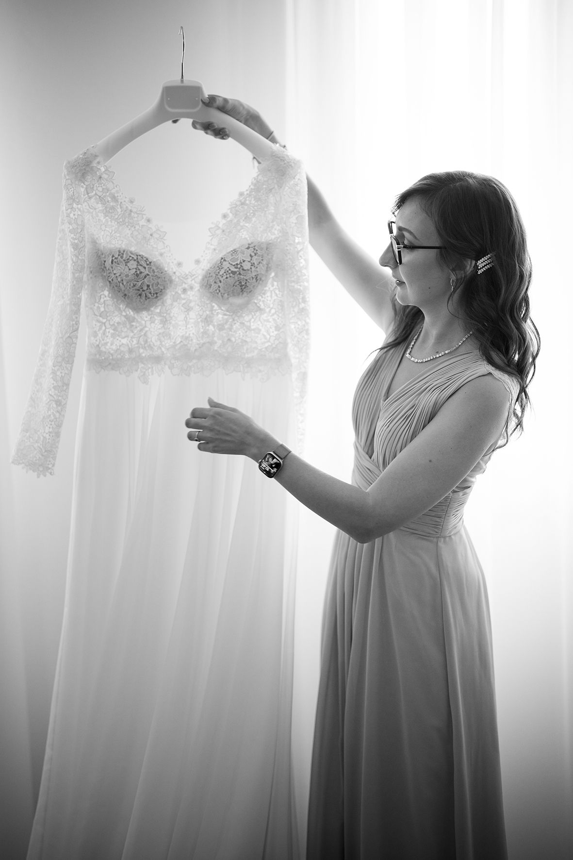 Silhouette of someone admiring a white wedding dress against backlit window.