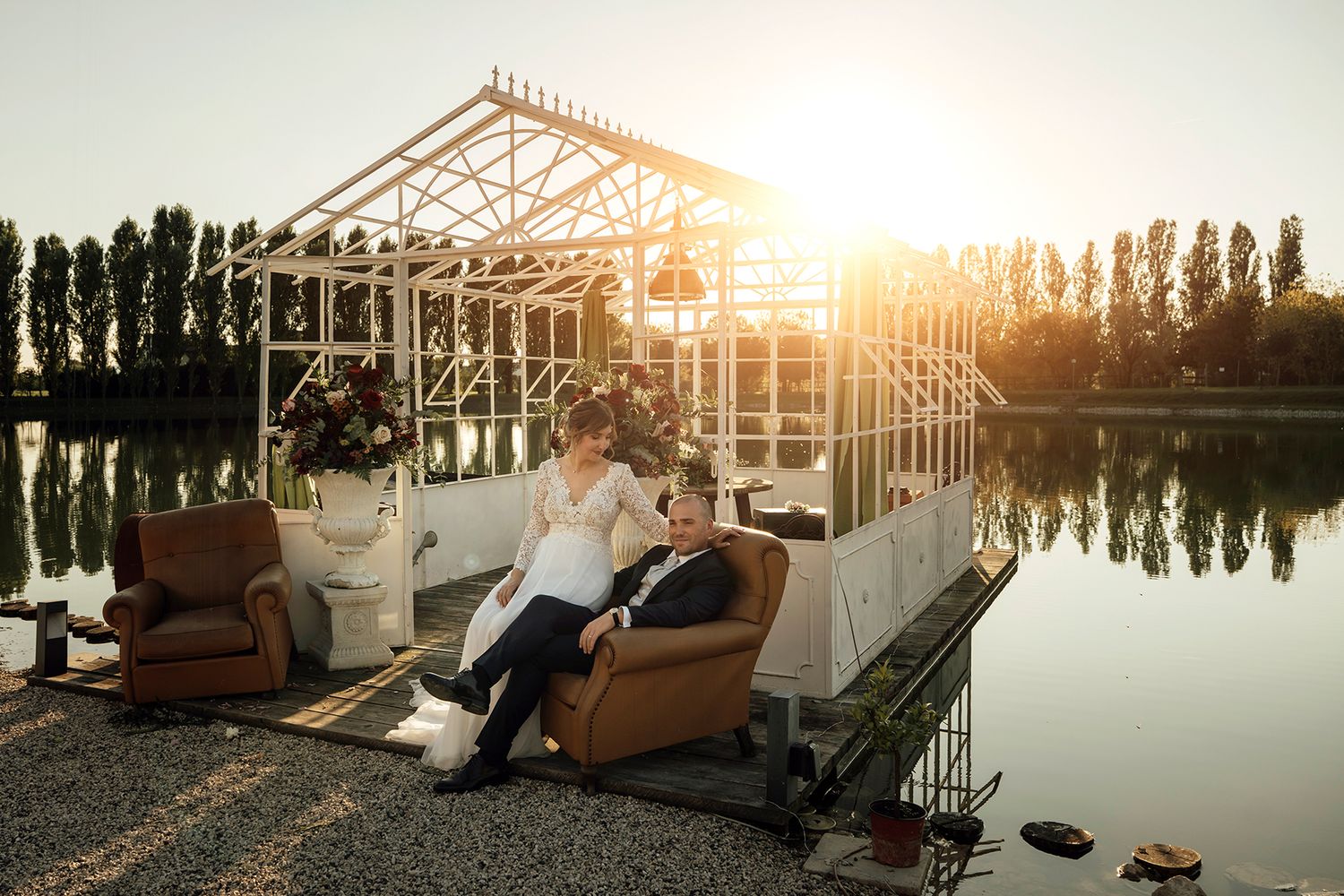 Sunset wedding photos by a greenhouse with beautiful golden light reflections.