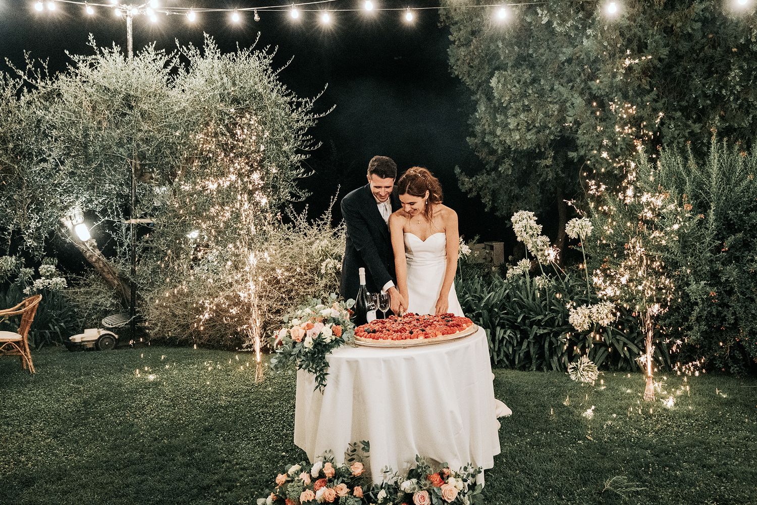 Evening garden wedding reception with twinkling lights and decorated tables at dusk.