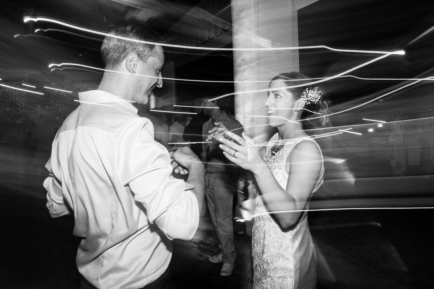 Motion-blurred black and white photos of people dancing at a celebration.