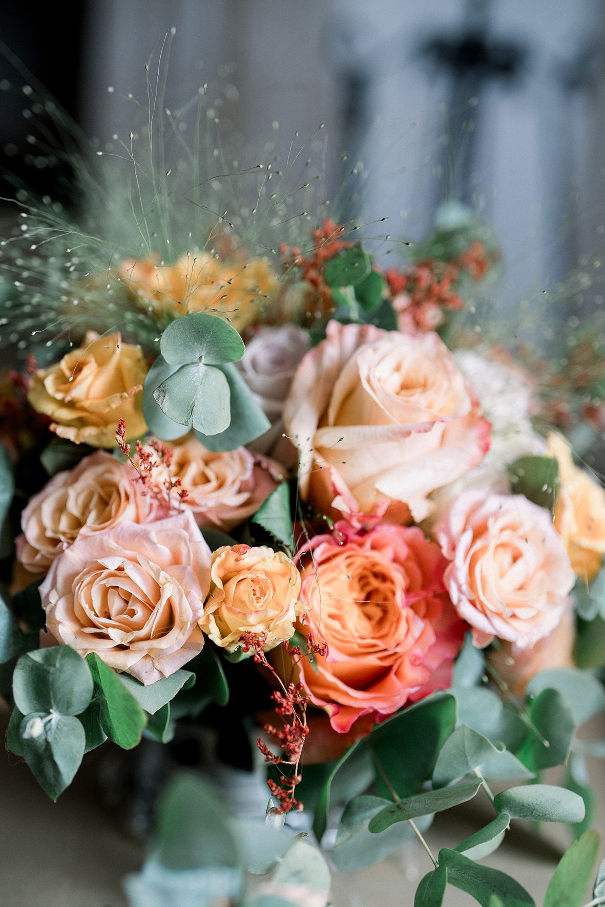 Beautiful arrangement of peach and coral roses with eucalyptus leaves.