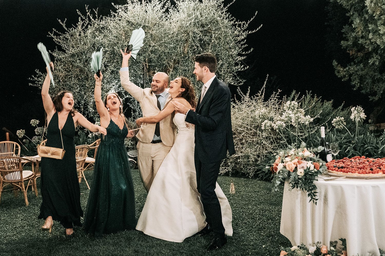 Outdoor wedding reception with string lights and white tables set up in a garden setting.