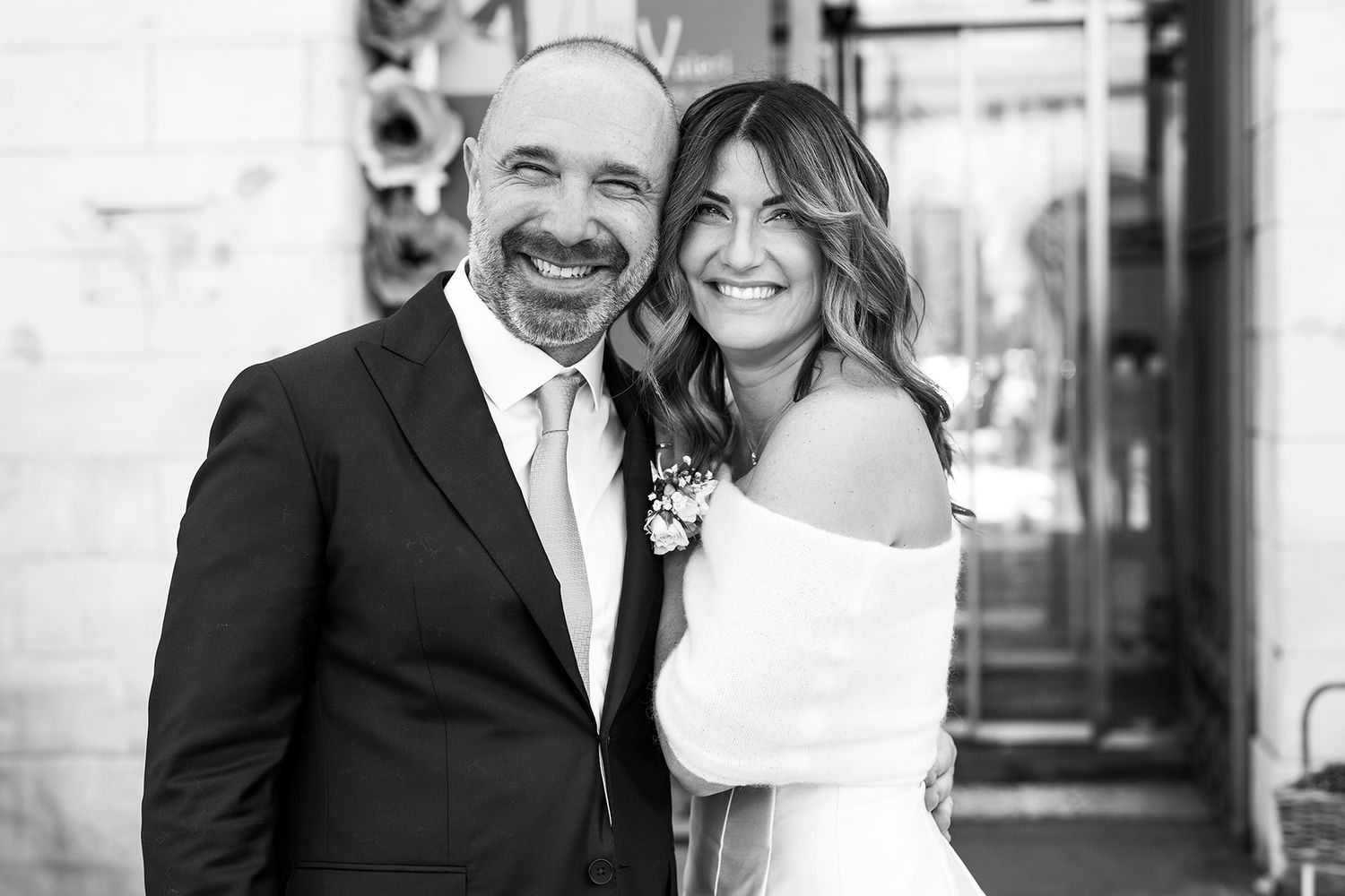 A couple in wedding attire sharing a joyful moment together in a black and white portrait.
