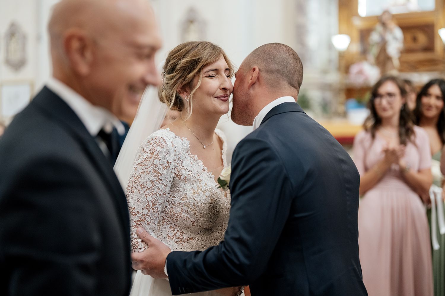 Wedding couple shares a tender embrace during their ceremony in a church setting.