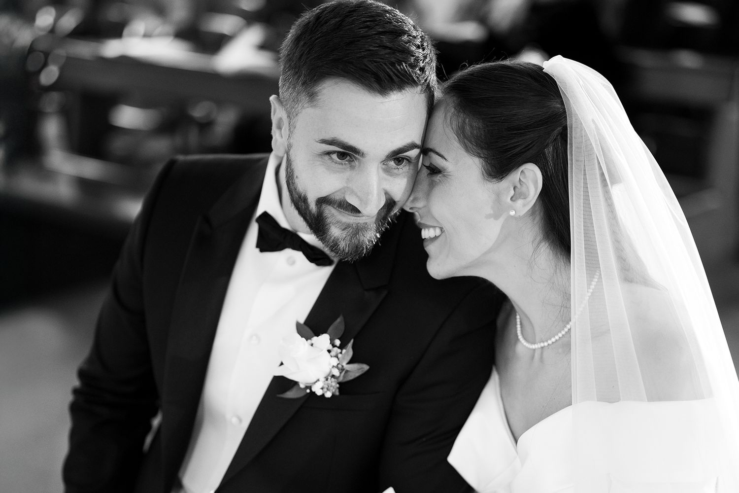 An intimate black and white portrait of newlyweds sharing a joyful moment during their wedding ceremony.