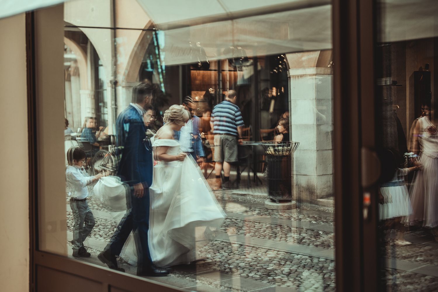 Wedding guests browsing storefronts along a historic colonnade.