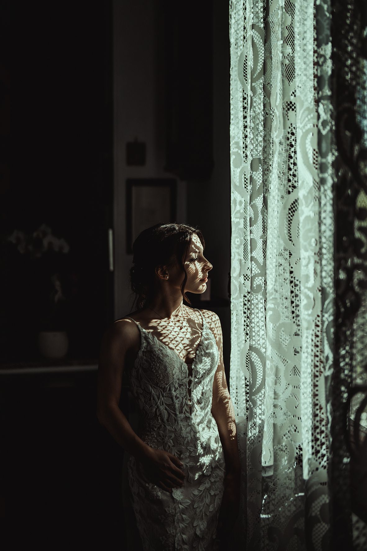 Sunlight streams through lace curtains creating an ethereal atmosphere in a dim room.