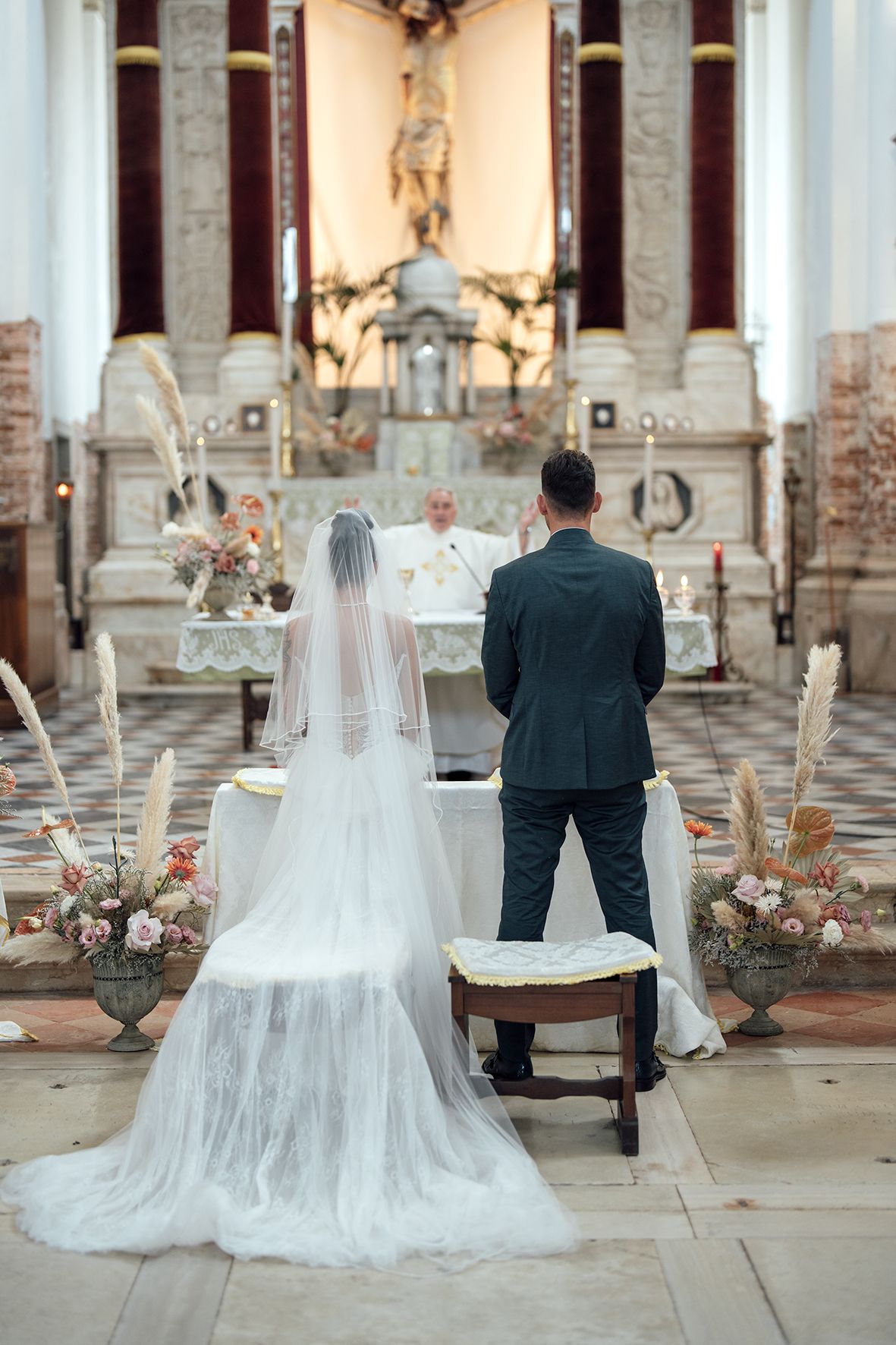 Couple seated on ornate church chairs during intimate ceremony moment.