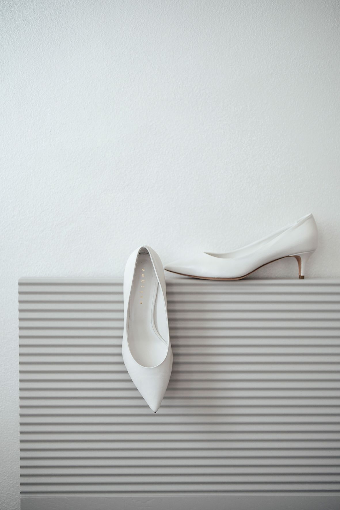 White elegant bridal shoes displayed on a striped surface with minimalist styling.