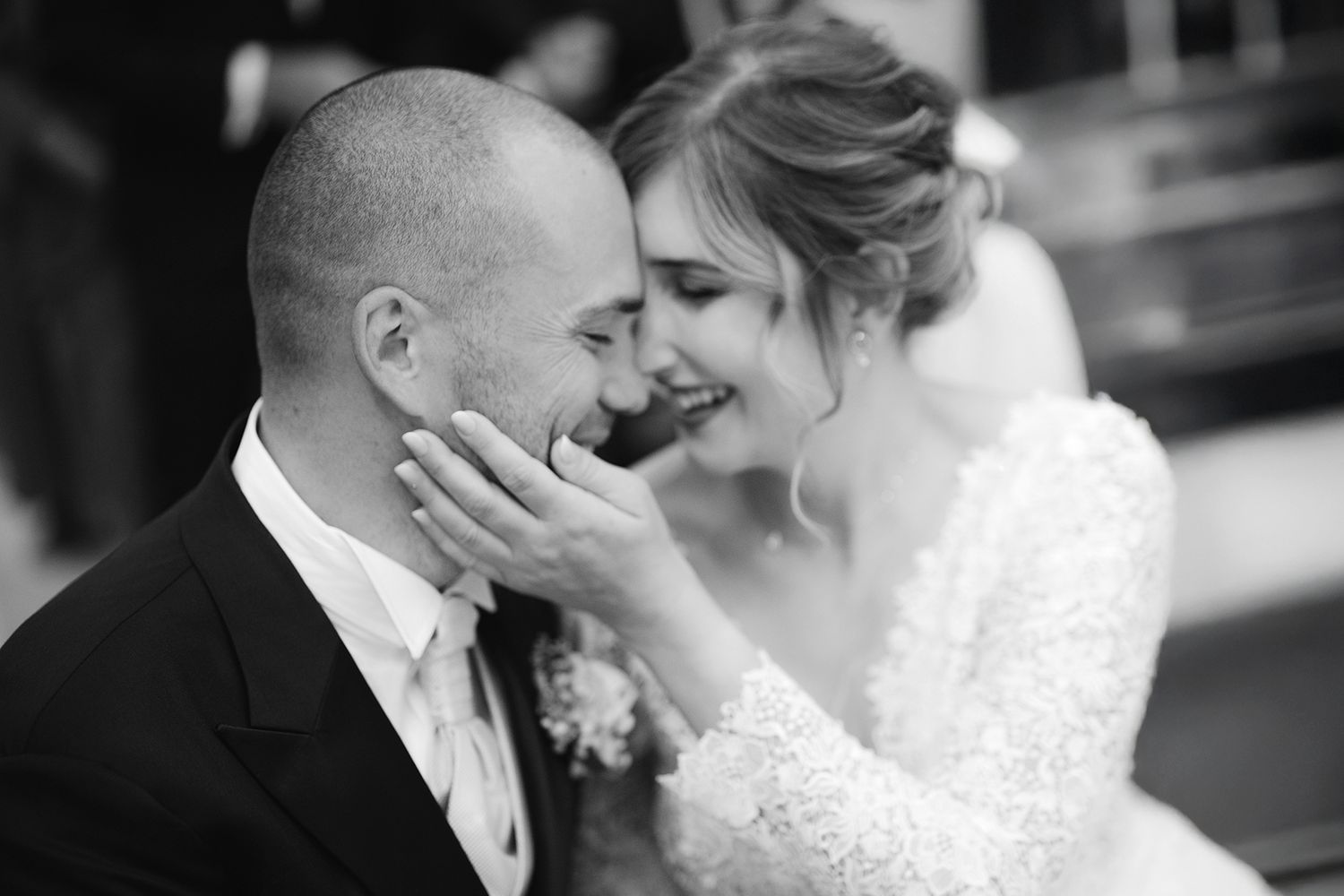 Black and white intimate moment between newlyweds sharing a tender laugh.