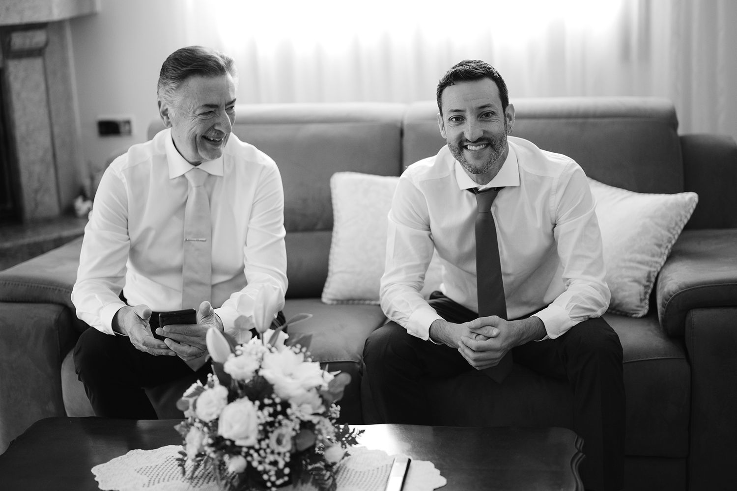 Group of people in white shirts laughing together on a couch.