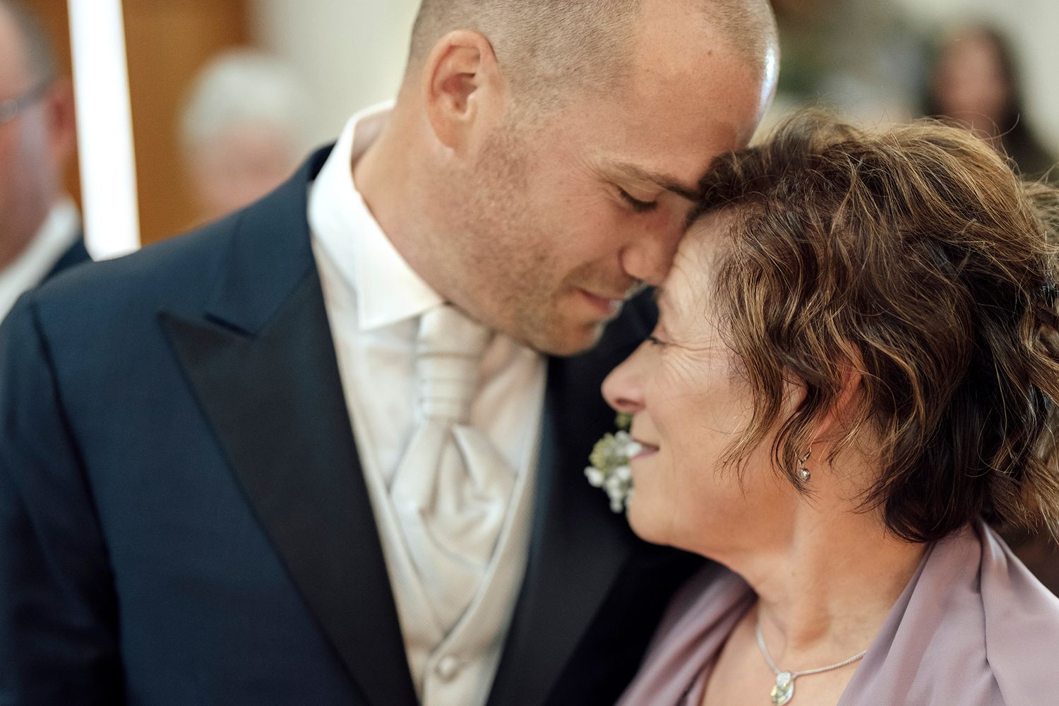 Candid moment of wedding guests sharing laughter in formal attire.