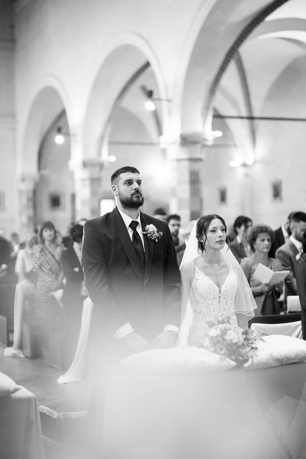 A black and white photo captures a solemn moment during a traditional church wedding ceremony.