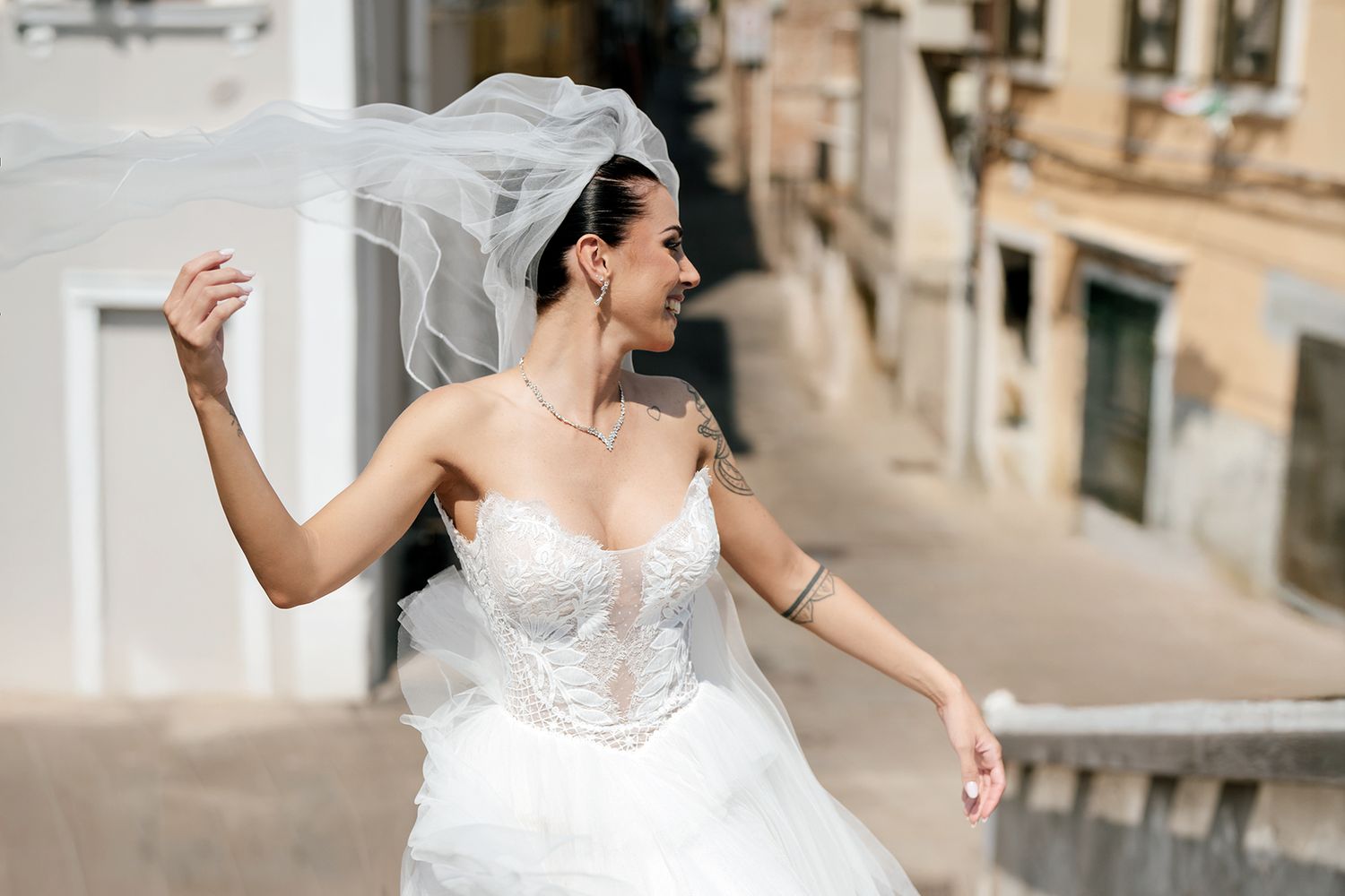 Bride in flowing white dress walking gracefully along stone pathway.
