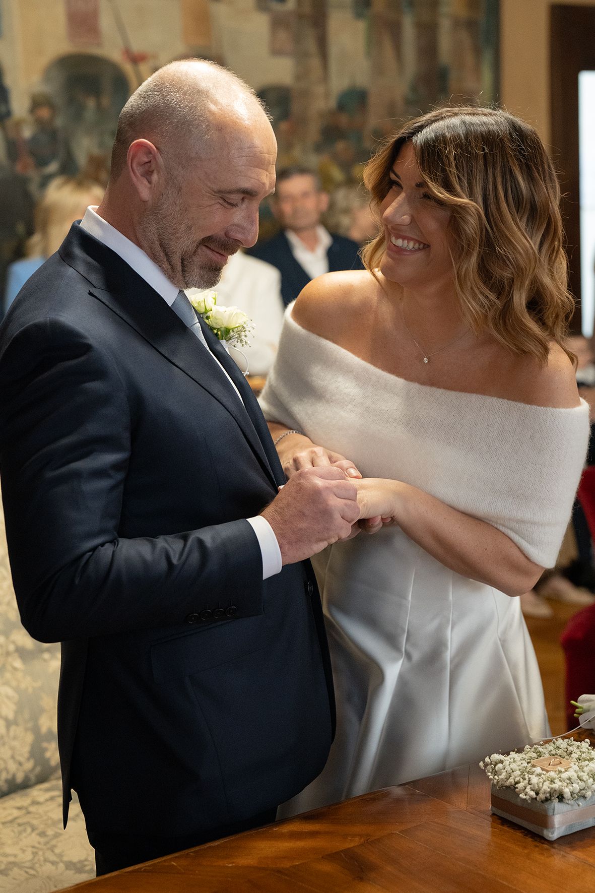 A tender moment during a wedding ceremony as couple exchanges rings at wooden table.