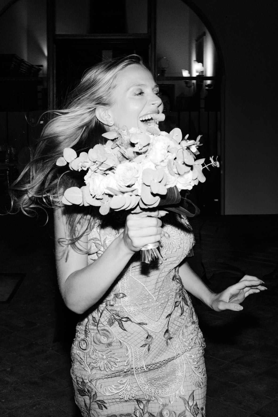 Black and white photo of someone in lace dress dancing with white floral decorations.