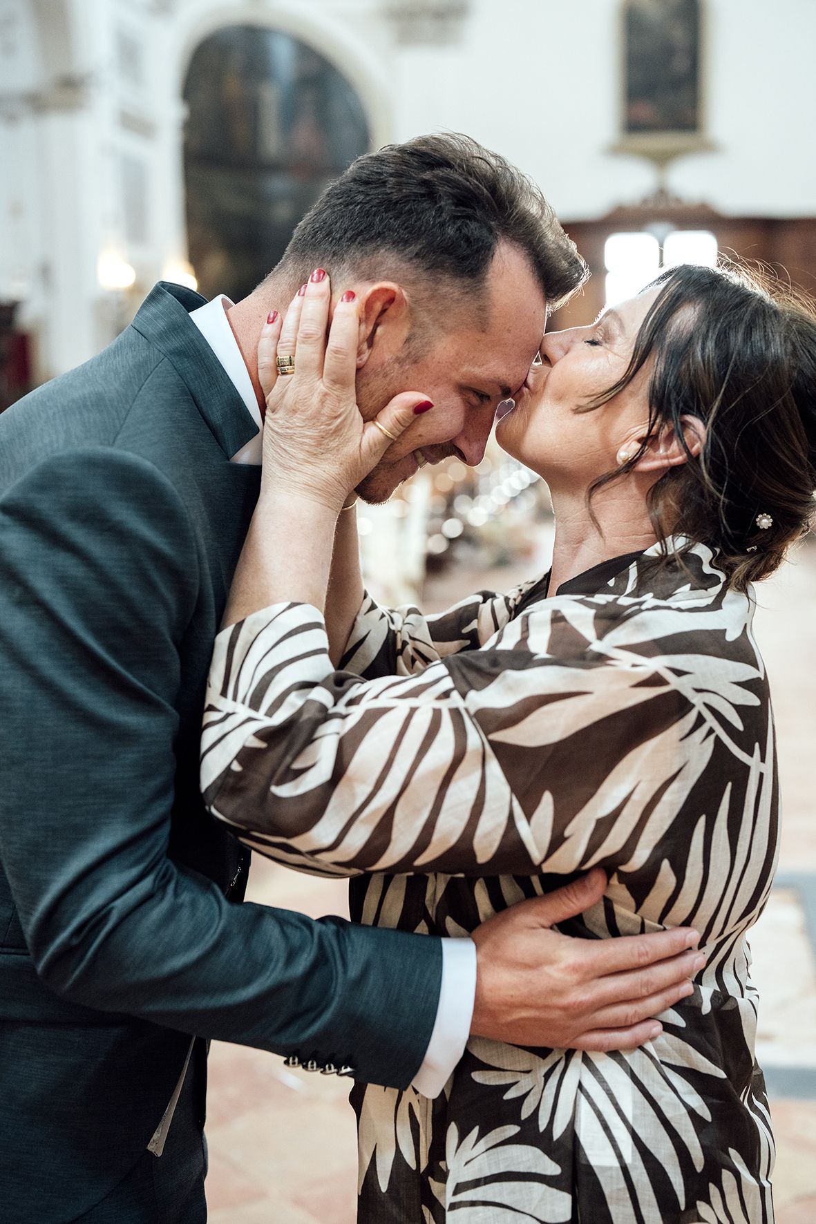 Tender moment between couple in formal wear inside church setting.