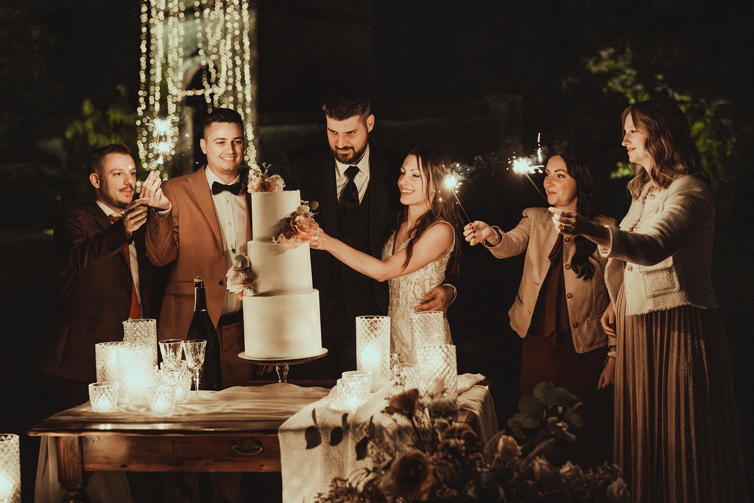 Wedding guests enjoying cake and desserts at an elegant reception celebration in dim lighting.