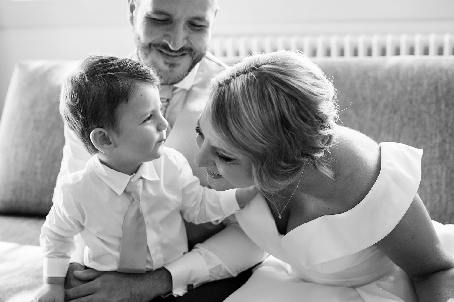 Intimate black and white family moment on couch during wedding day.