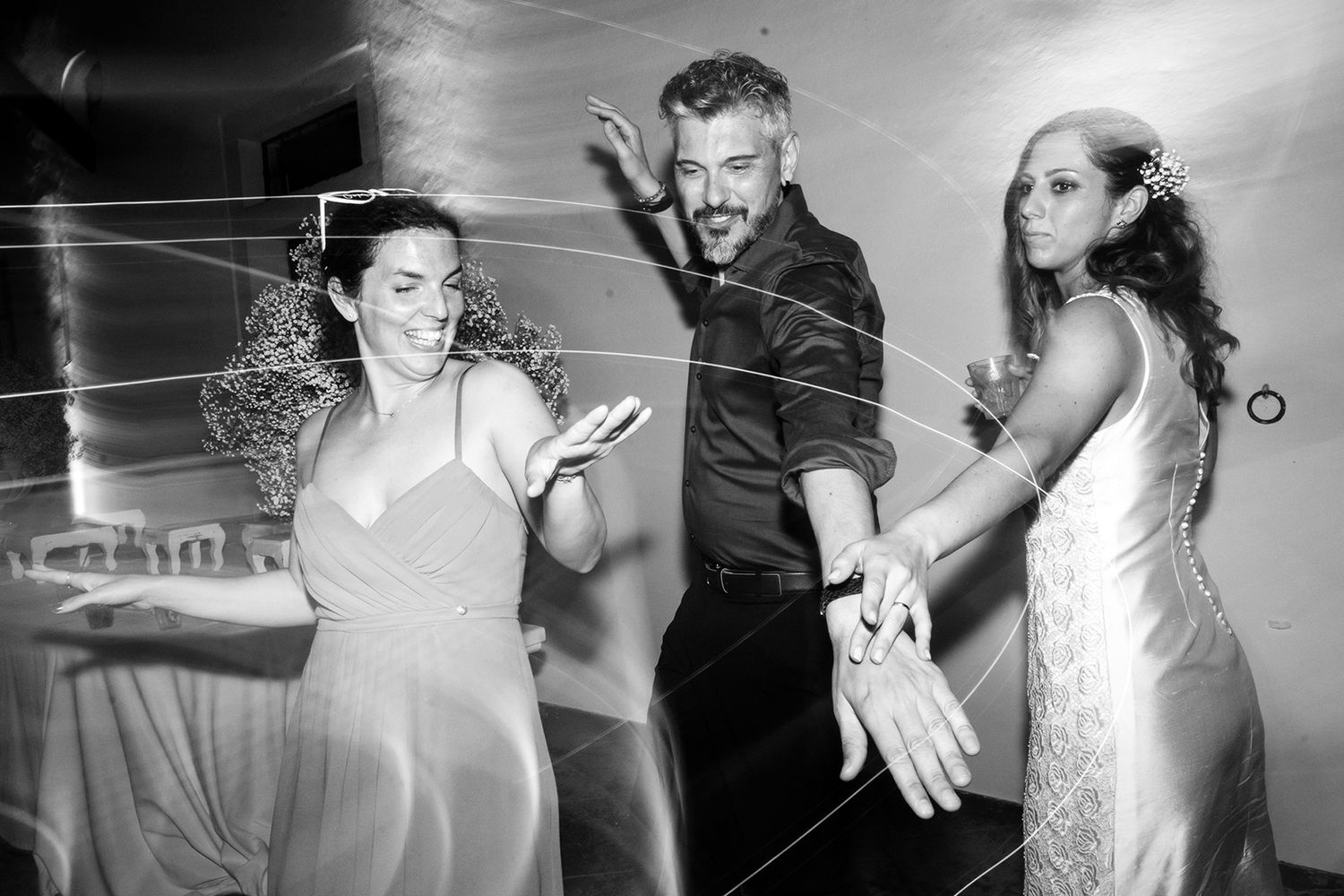 Artistic black and white photo capturing motion blur of dancers at a celebration.