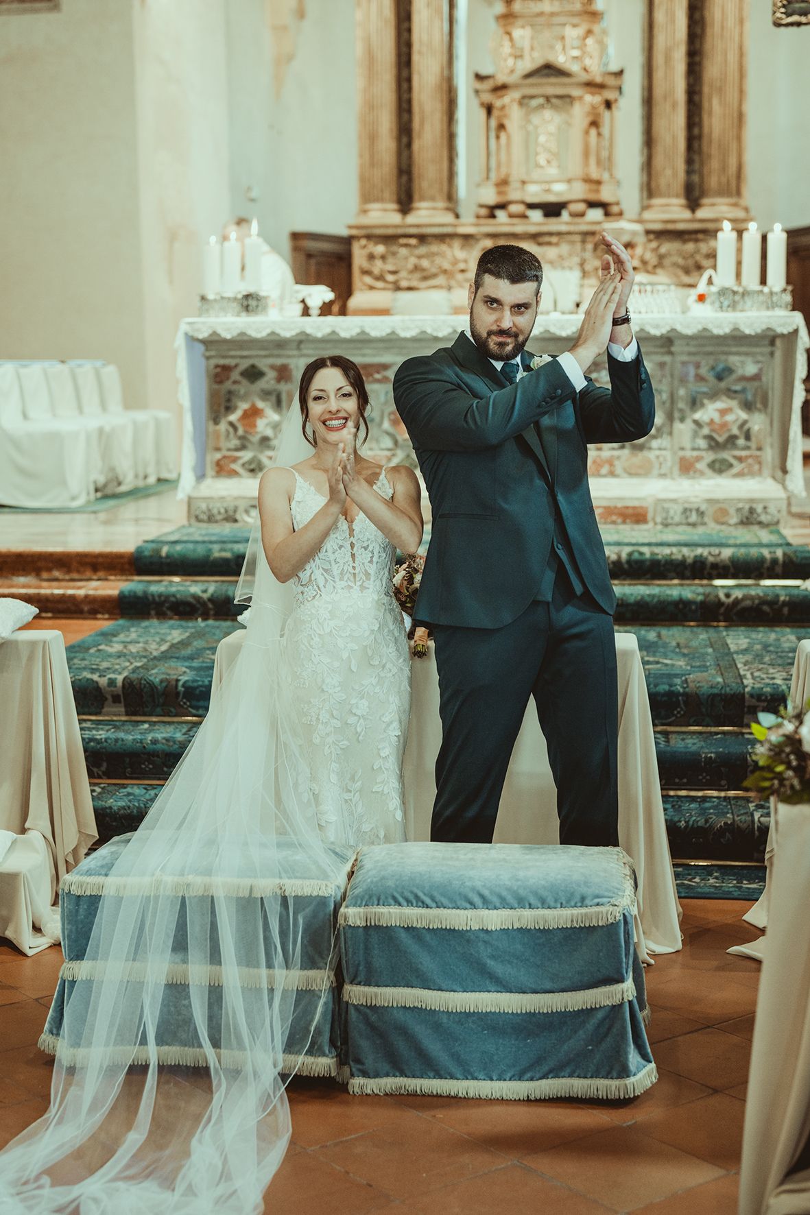 Newlyweds celebrate with raised hands at the altar of a beautifully decorated church.