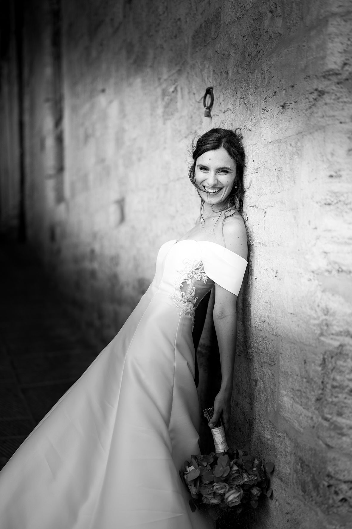 Artistic black and white bridal portraits against a textured stone wall.