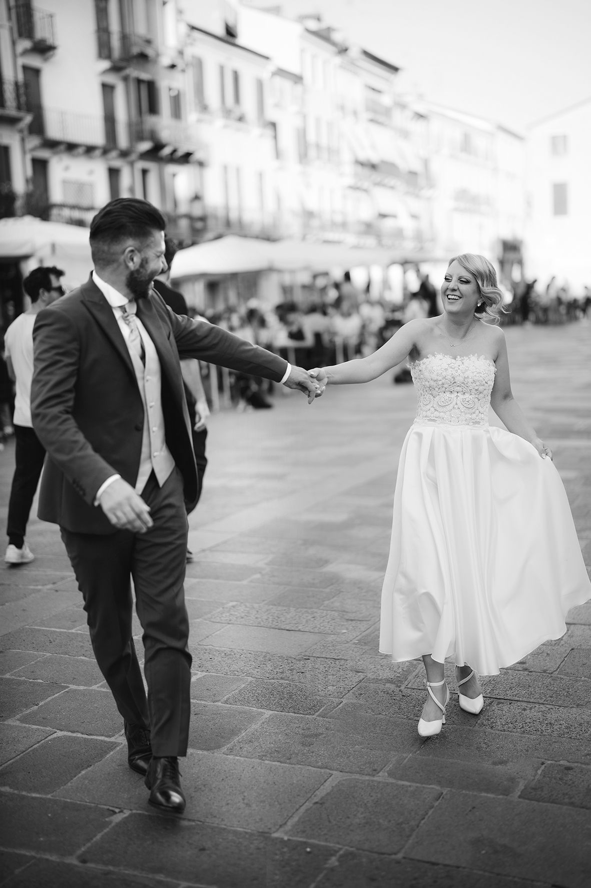A joyful dancing moment captured in black and white on a European plaza.
