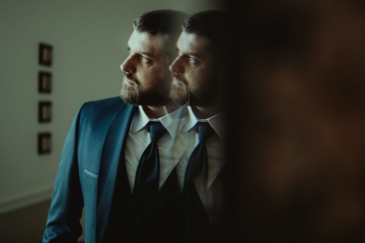 Stylish men in suits pose in moody lighting against dark backgrounds.