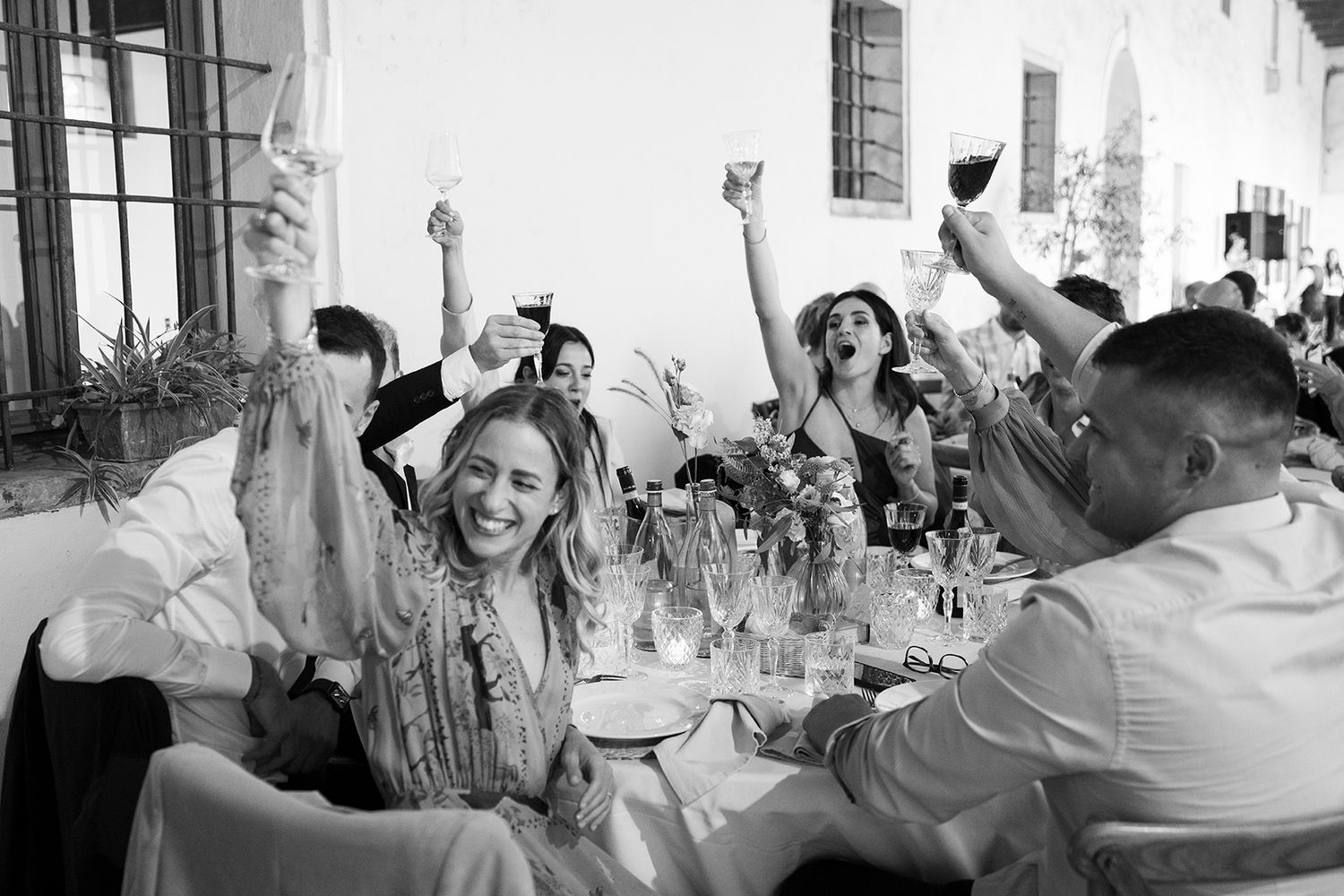 Joyful wedding reception with guests raising their hands in celebration.