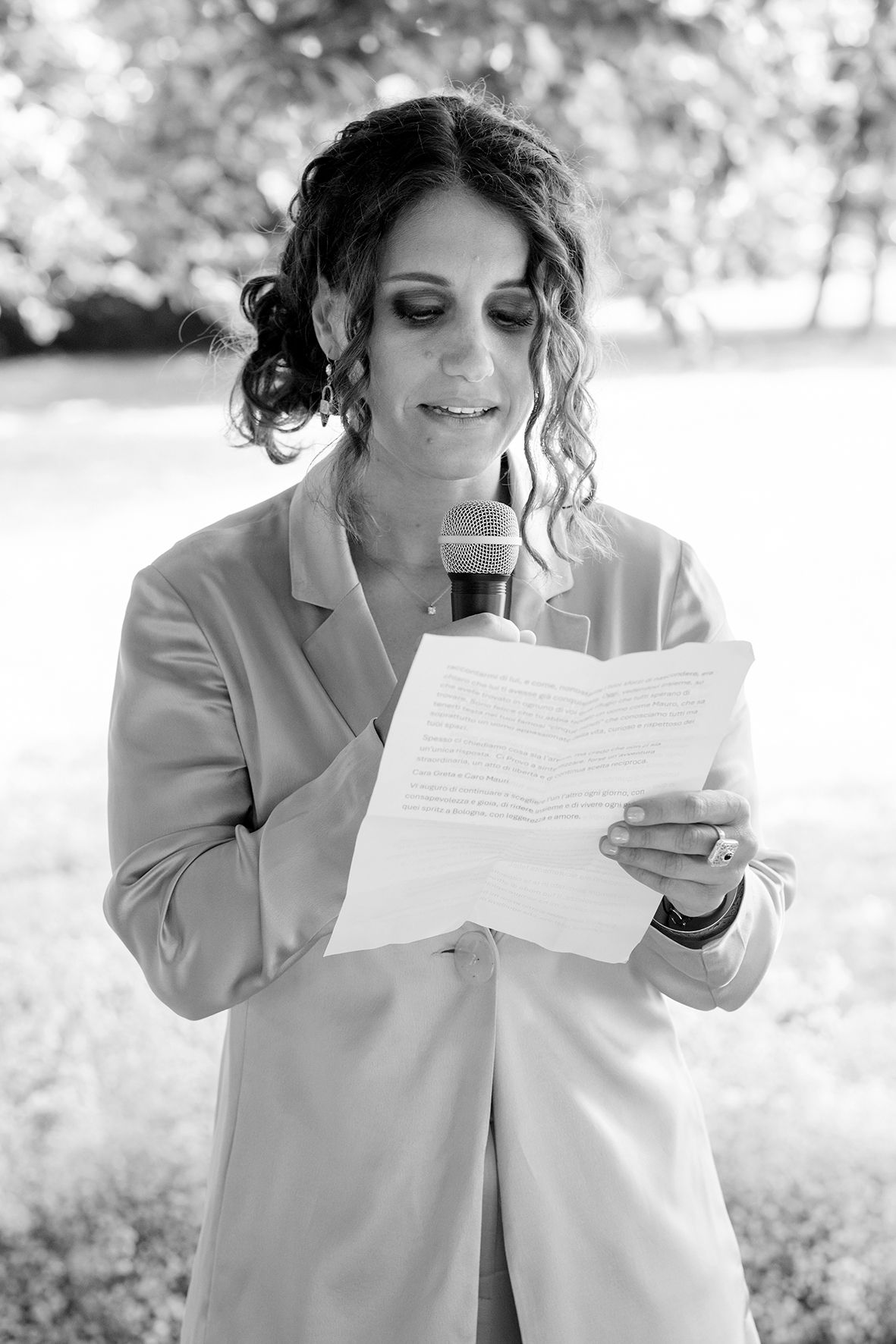 Person in light colored clothing reading documents while holding a beverage.