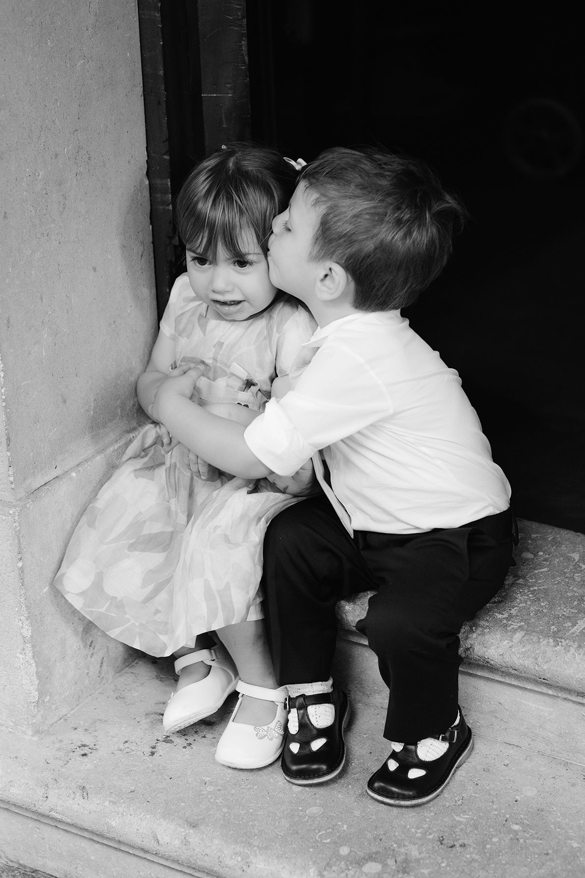 Sweet black and white photo series of young children sharing an innocent kiss on stone steps.