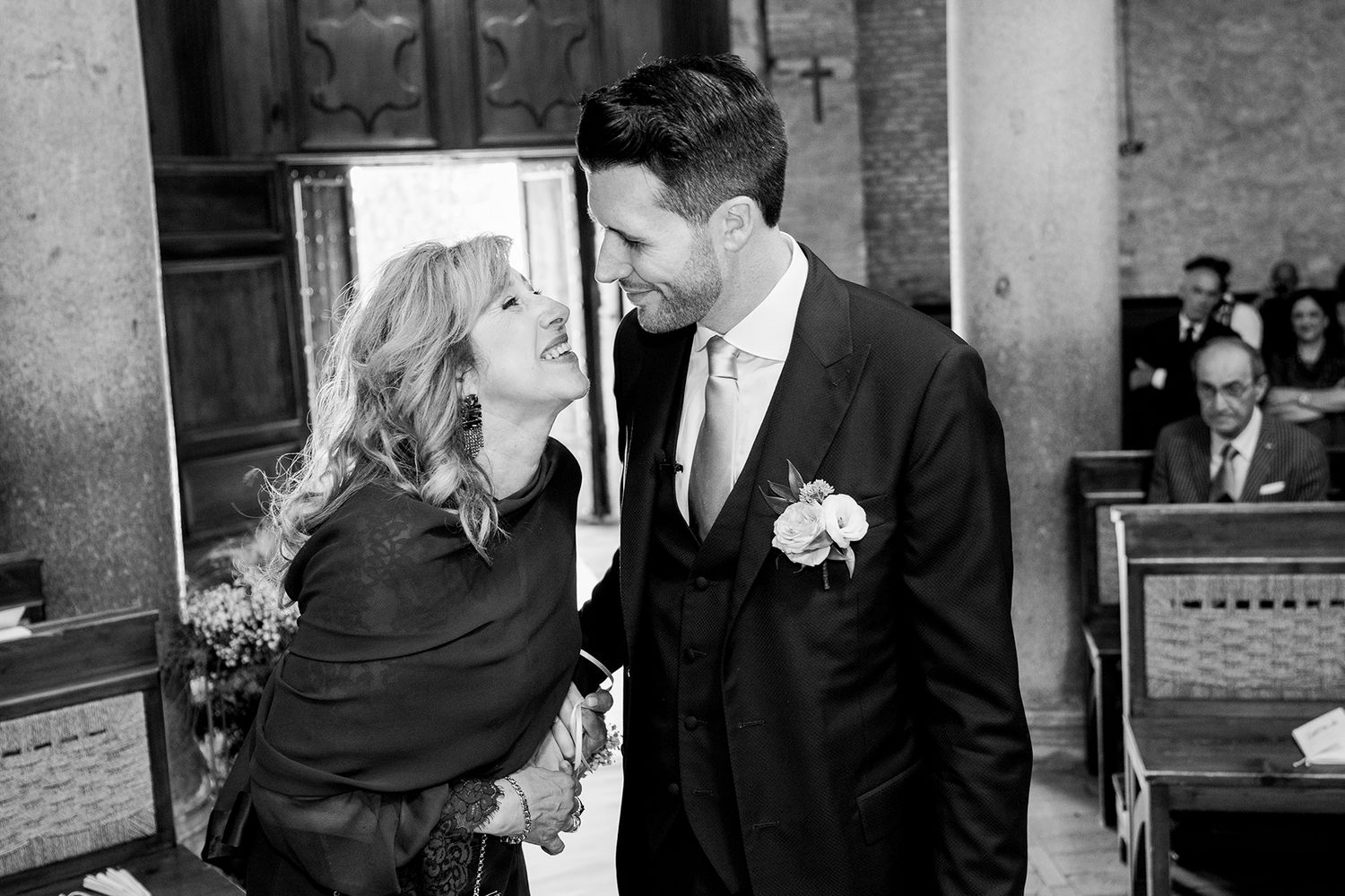 Wedding party members share candid moments and laughter in formal attire.